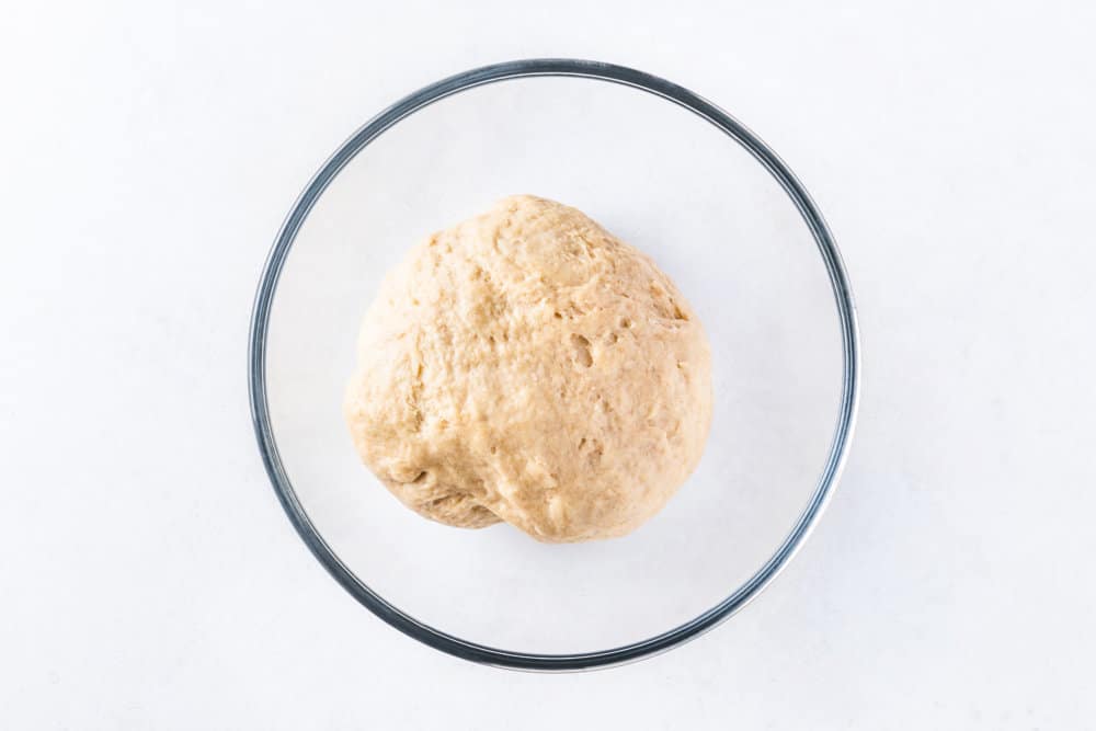 Dough for Russian vatrushka buns in a glass bowl.