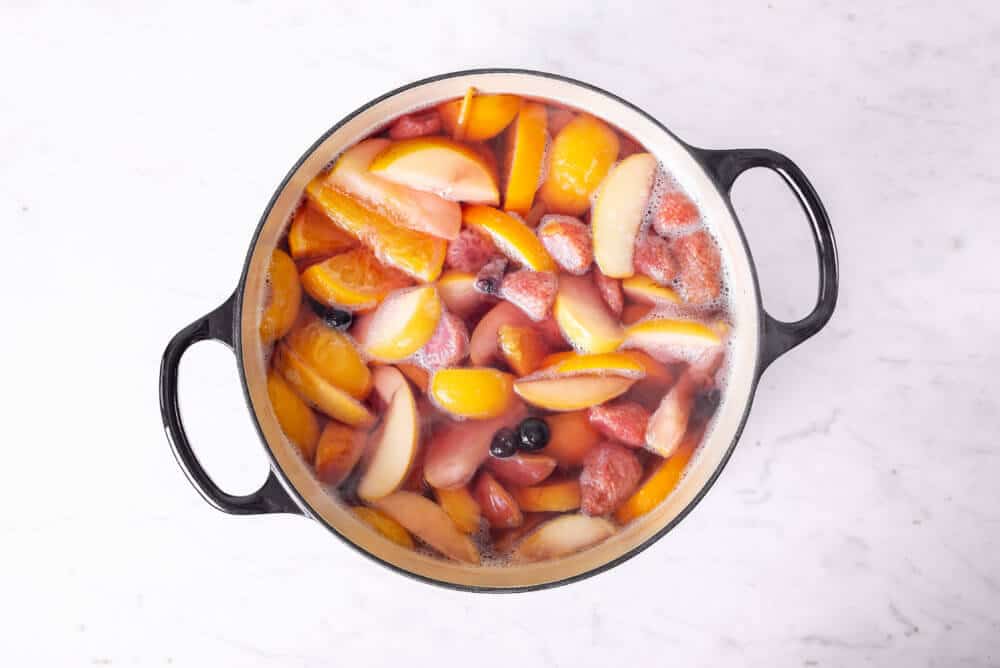 chopped fruit and water simmering together in a large pot.