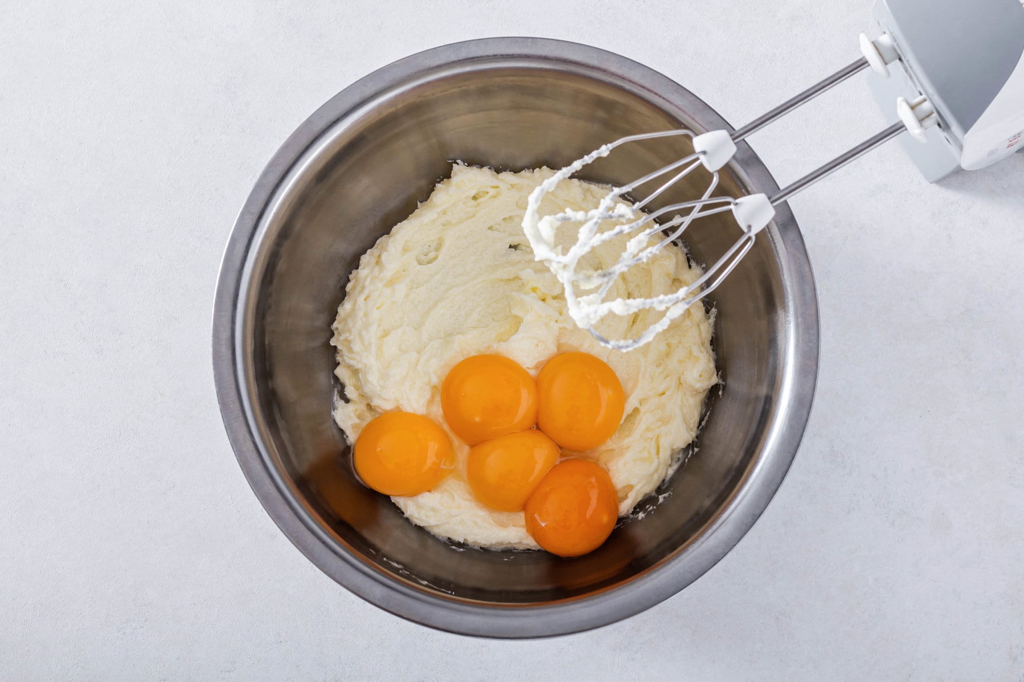 butter-sugar-and-egg-yolks-being-mixed-in-a-silver-bowl-with-hand-mixer