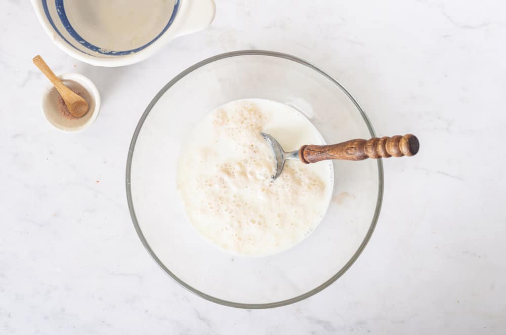 dough-process-for-piroshki-in-a-glass-bowl-with-a-spoon-with-another-empty-bowl-on-the-side-and-a-small-bowl-of-salt