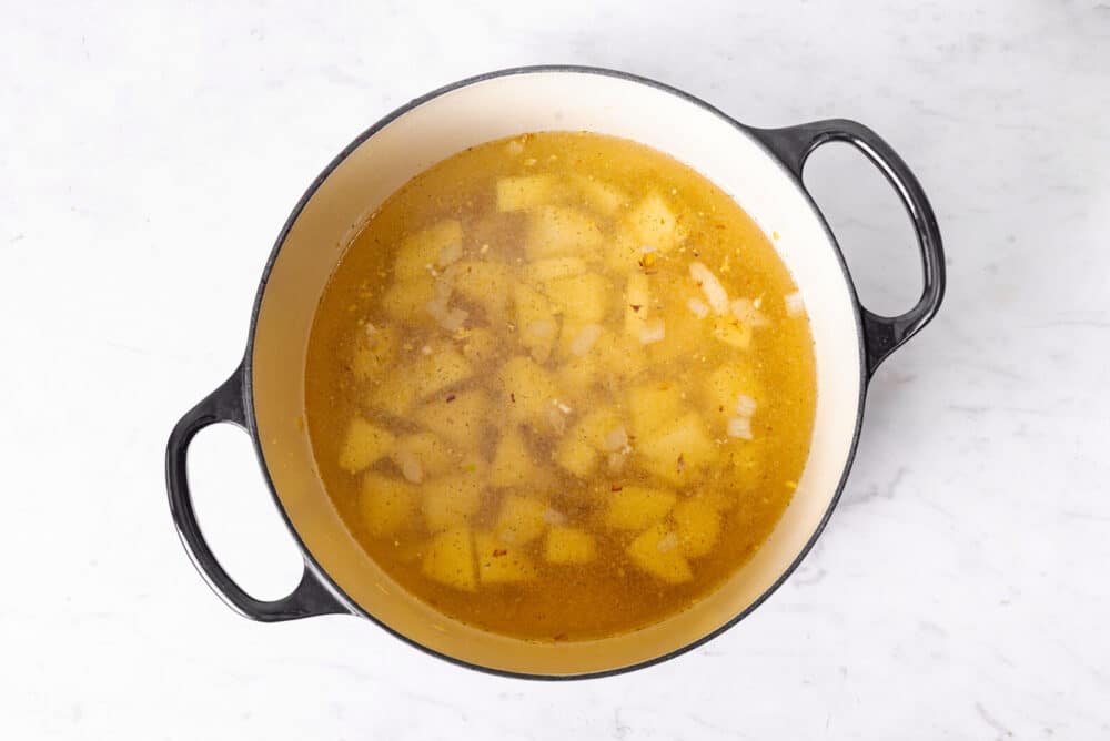 potatoes cooking in a broth in a large pot.