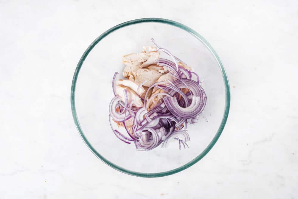 red onion and chicken in a glass bowl.