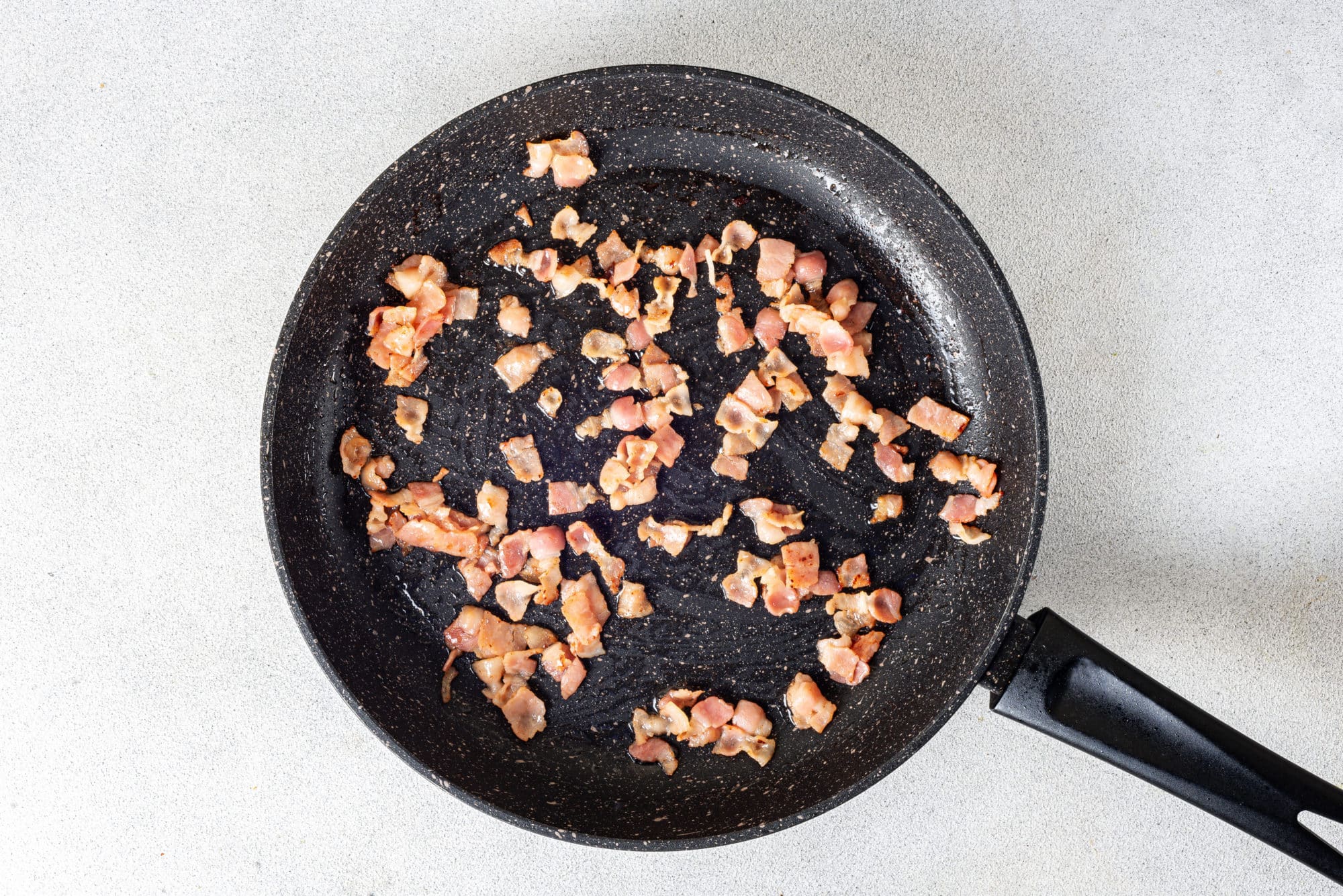 sauteed bacon in a black skillet.