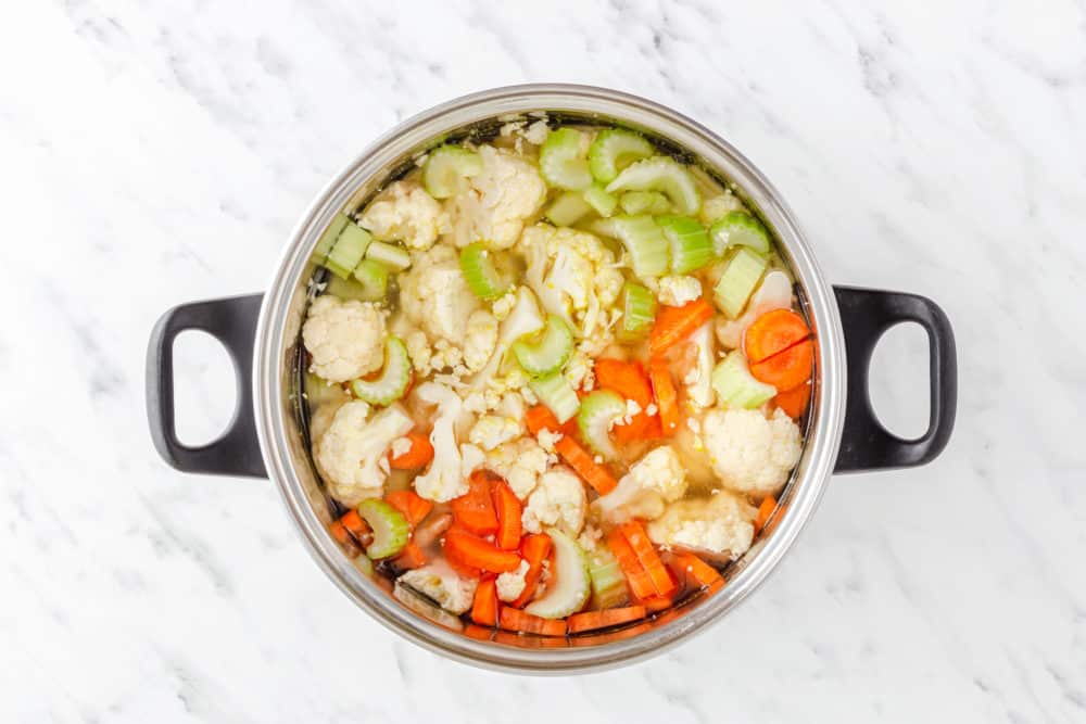 soup ingredients cauliflower celery carrots and onion in a large soup pot.