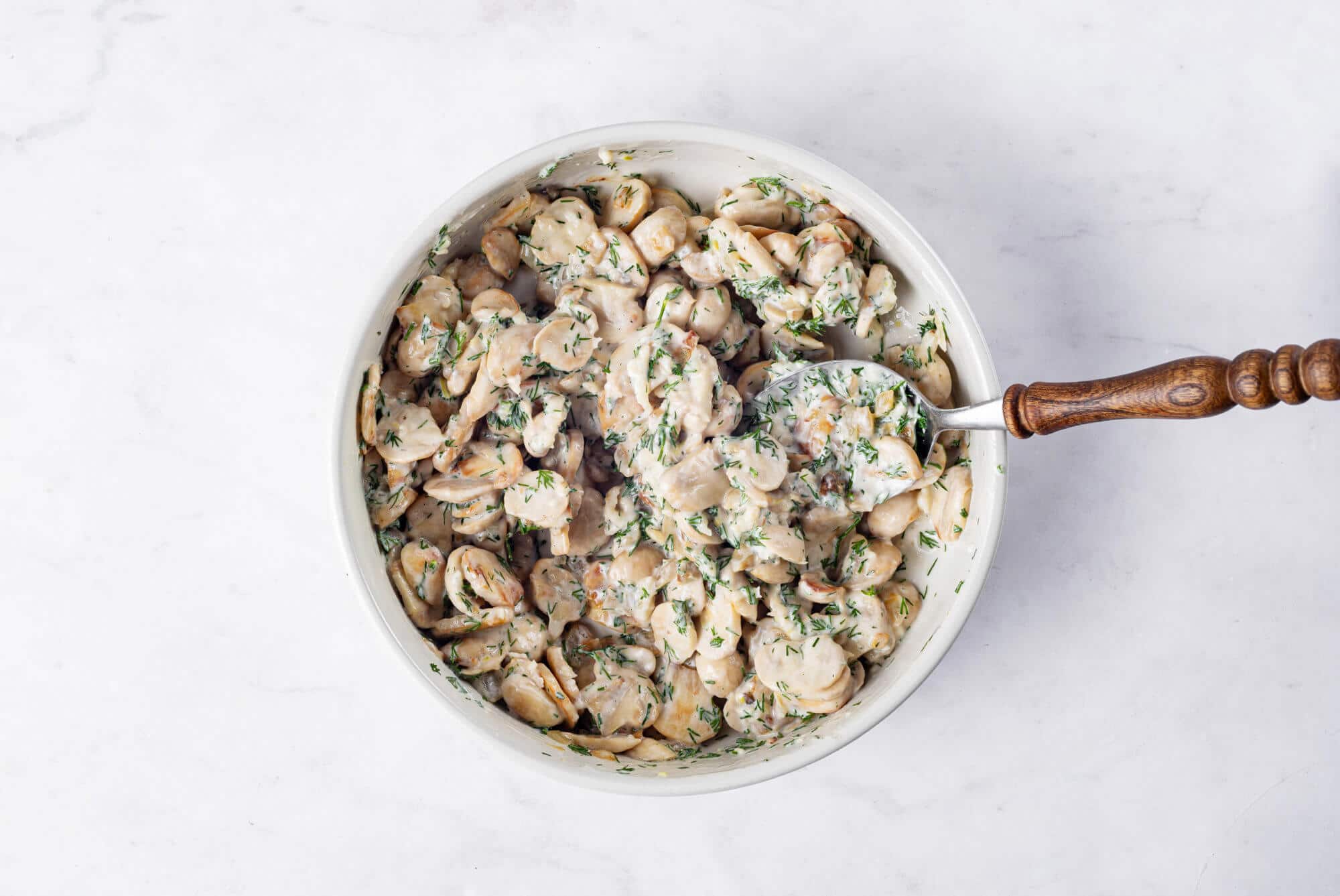 Mushroom crostini mix in a white bowl with a spoon.