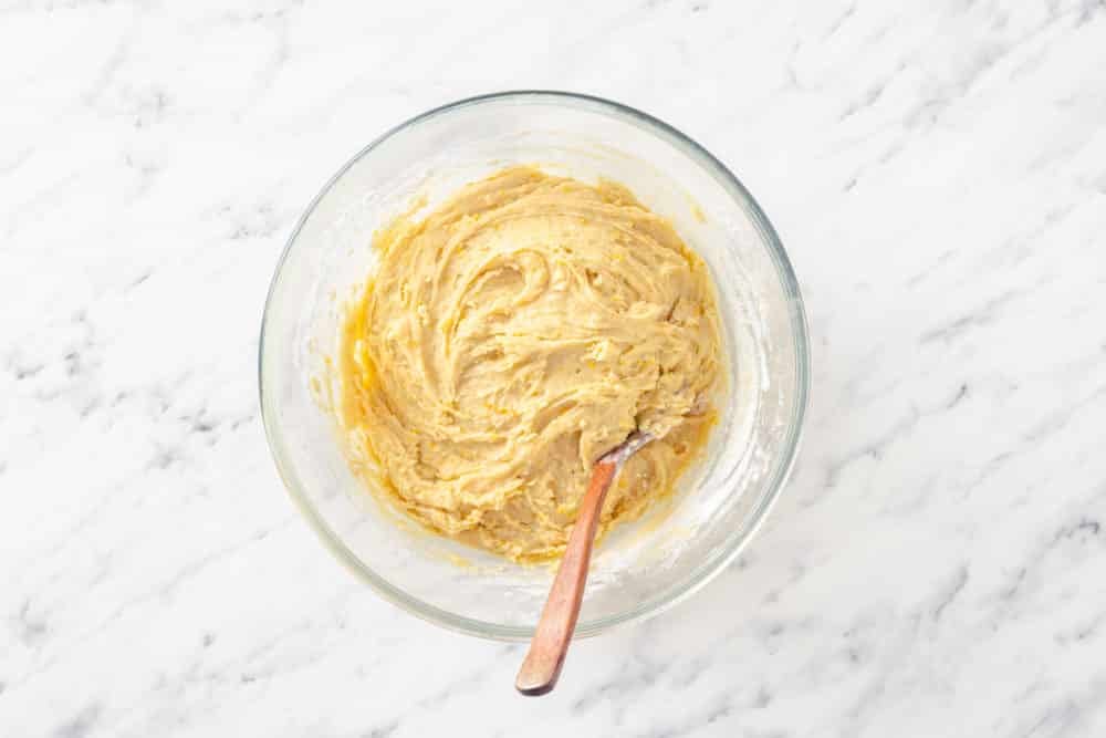 a glass bowl with batter and a wooden spoon in it.