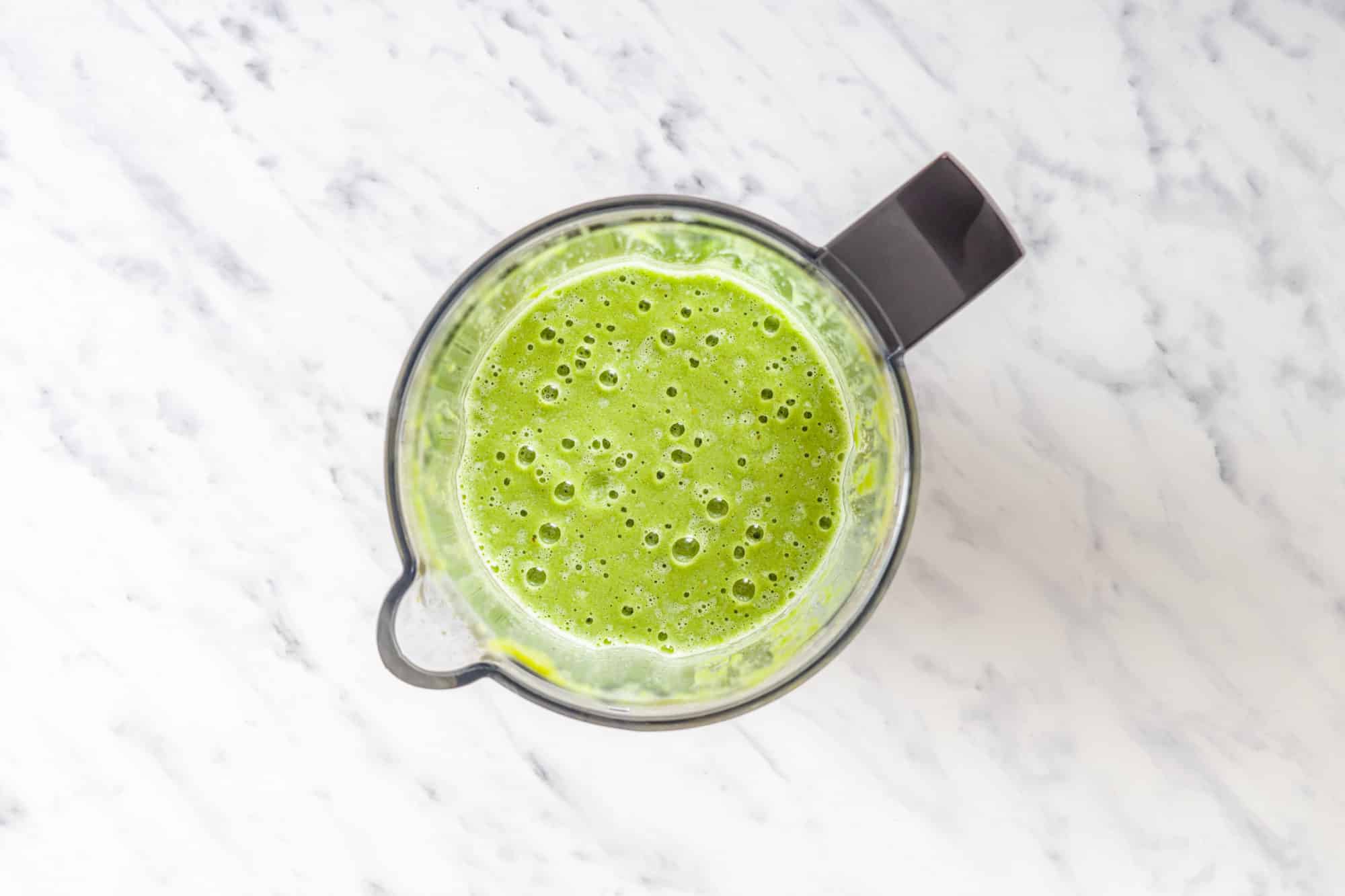 blended green smoothie in a blender top view.