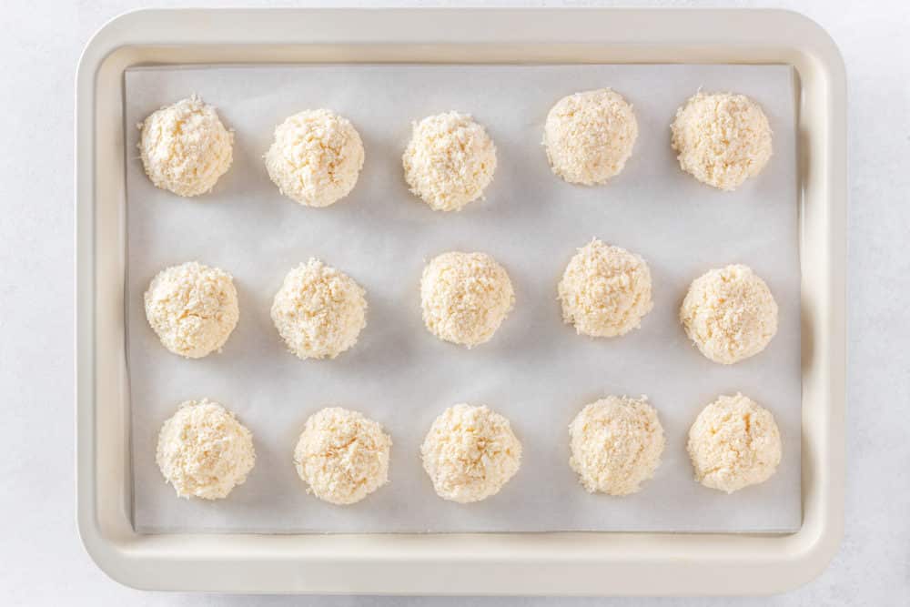 Unbaked macaroons on a baking tray with parchment paper.