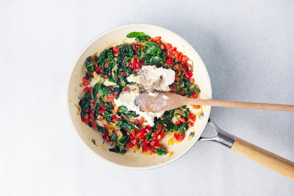 veggies mixing with cream in a skillet sauteing all together.