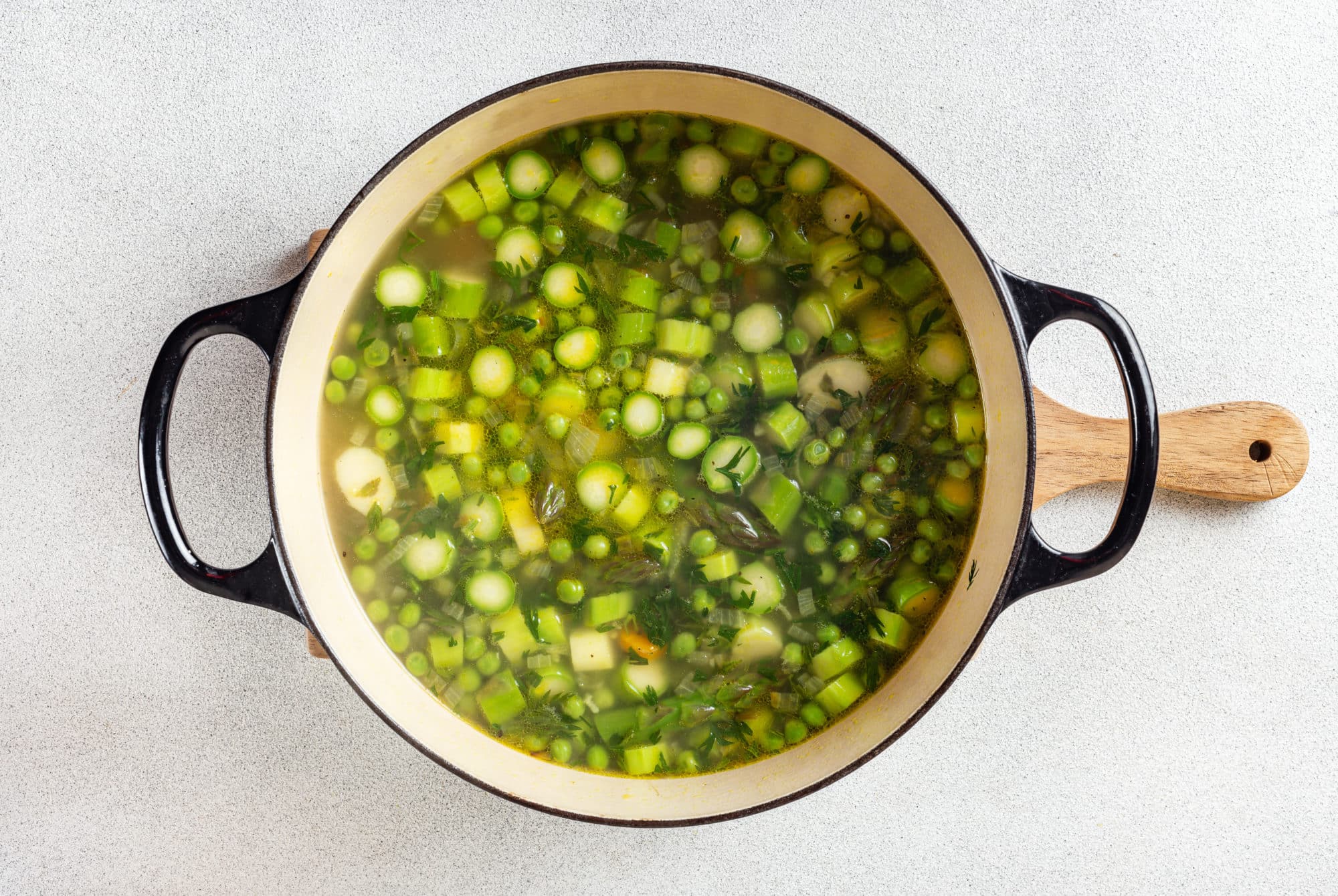 asparagus soup with chopped asparagus in a soup pot on a wooden board.