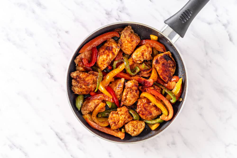 sauteing chicken and bell peppers in a skillet.