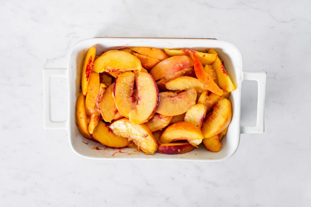 Sliced peaches in a baking tray.