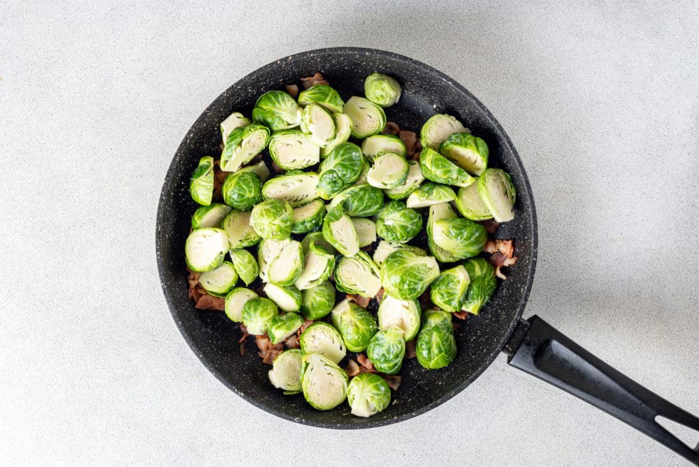 a skillet with brussels sprouts and bacon in it.