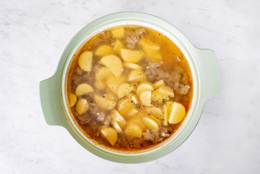 zuppa toscana potatoes and sausage cooking in a large soup pot.