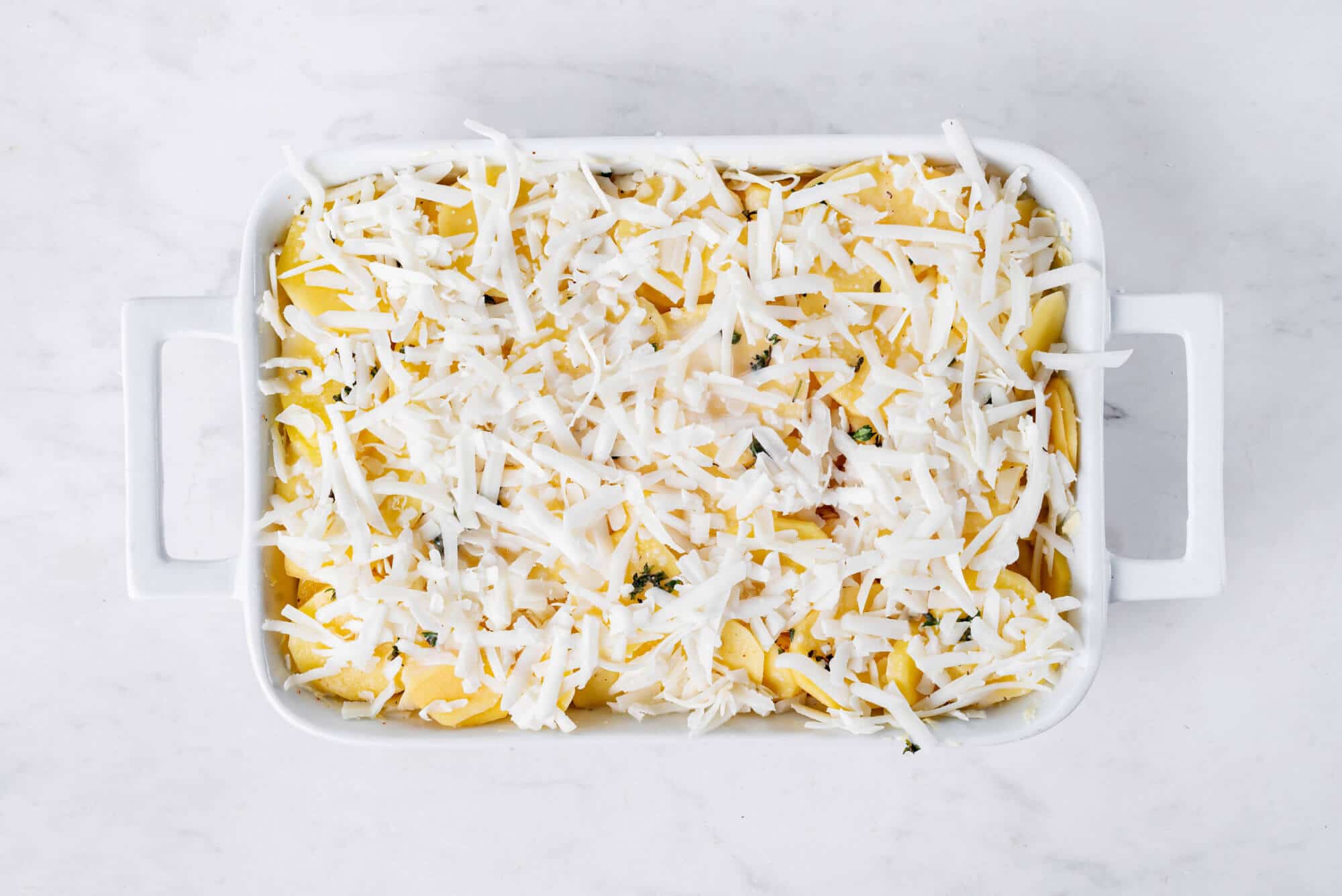 uncooked-scalloped-potatoes-in-baking-dish-topped-with-cheese