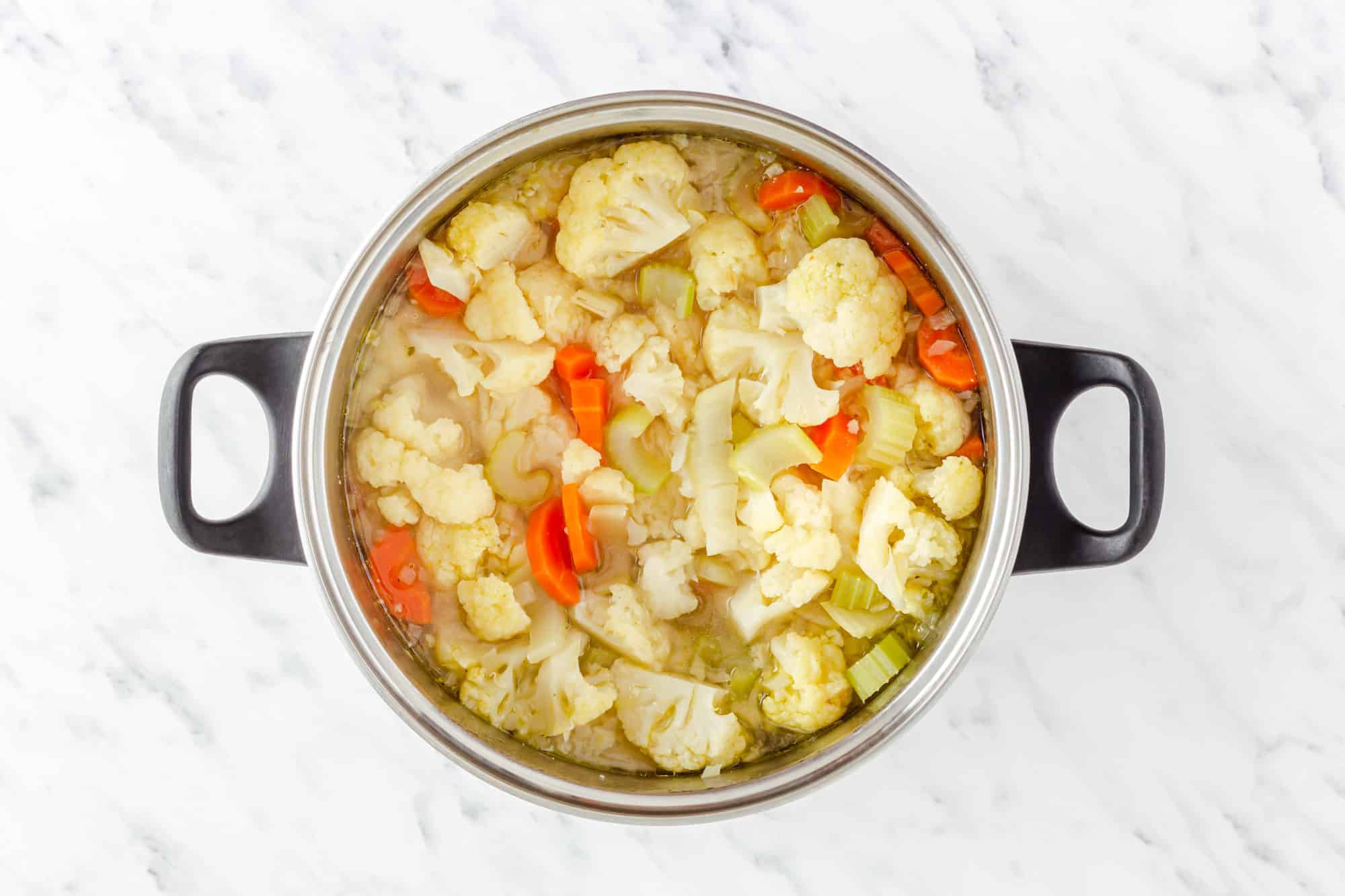 vegetable soup ingredients in a pot with broth.