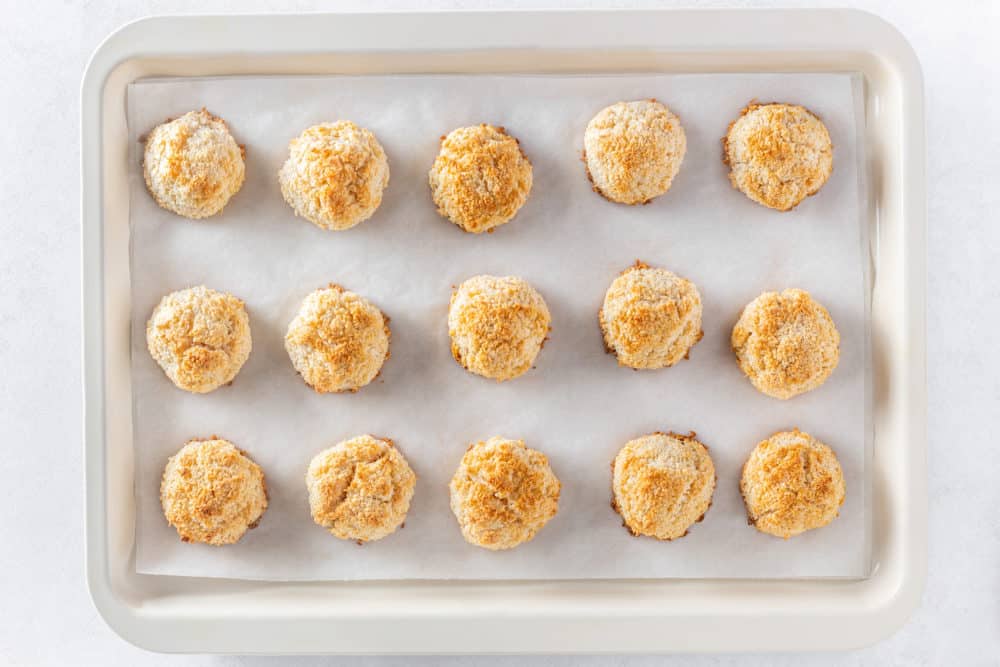 Macaroons fresh out of the oven on a baking tray with parchment paper.