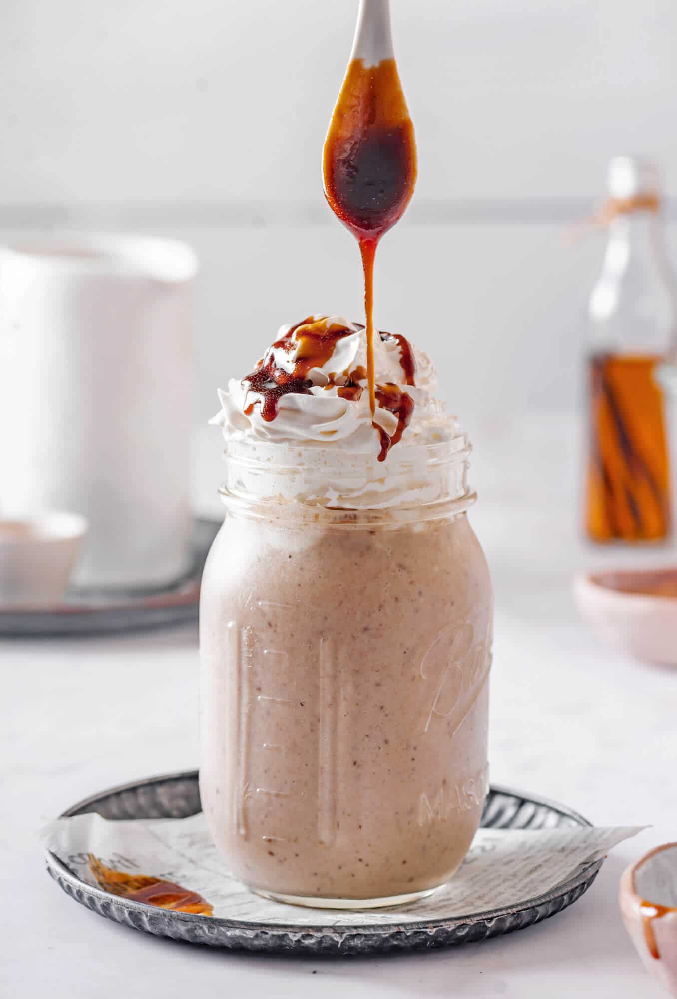 caramel smoothie in a mason jar with cream and a drizzle of caramel. 