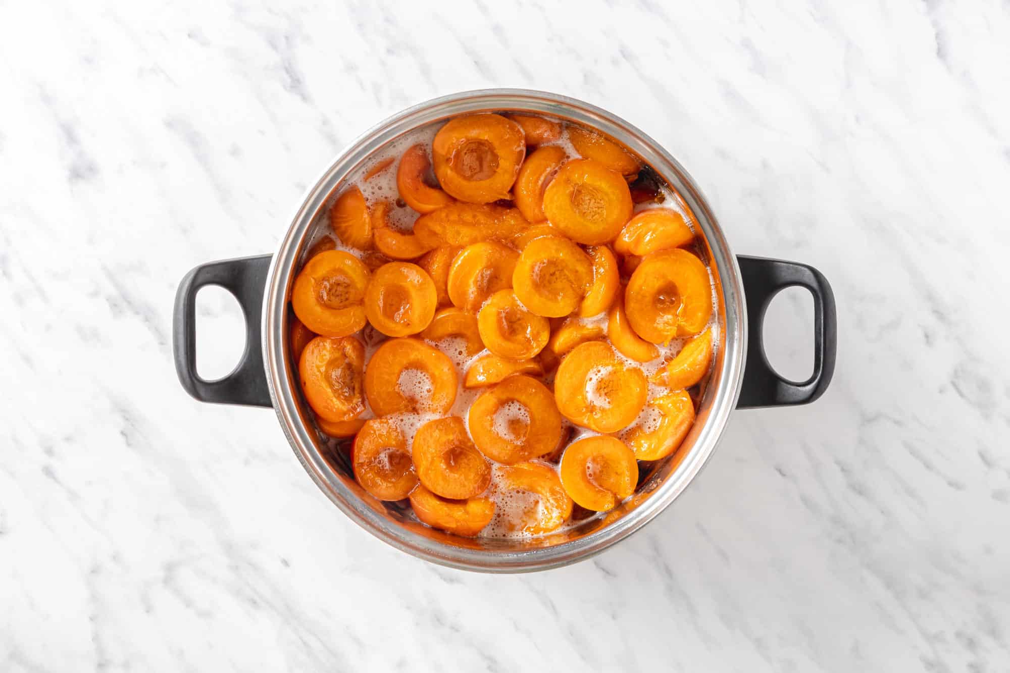 a pot with halved apricots and water.