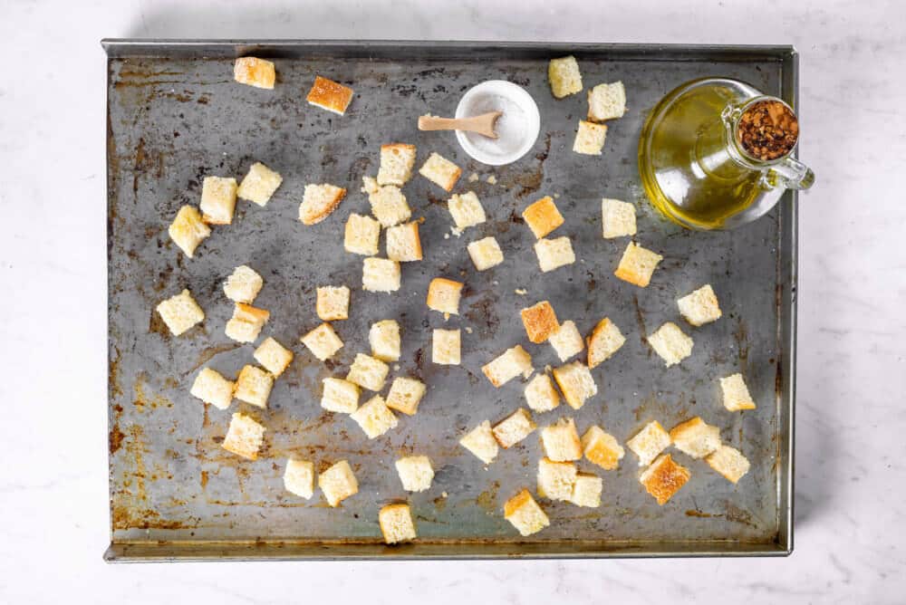 croutons ready to bake on a tray with olive oil and salt.