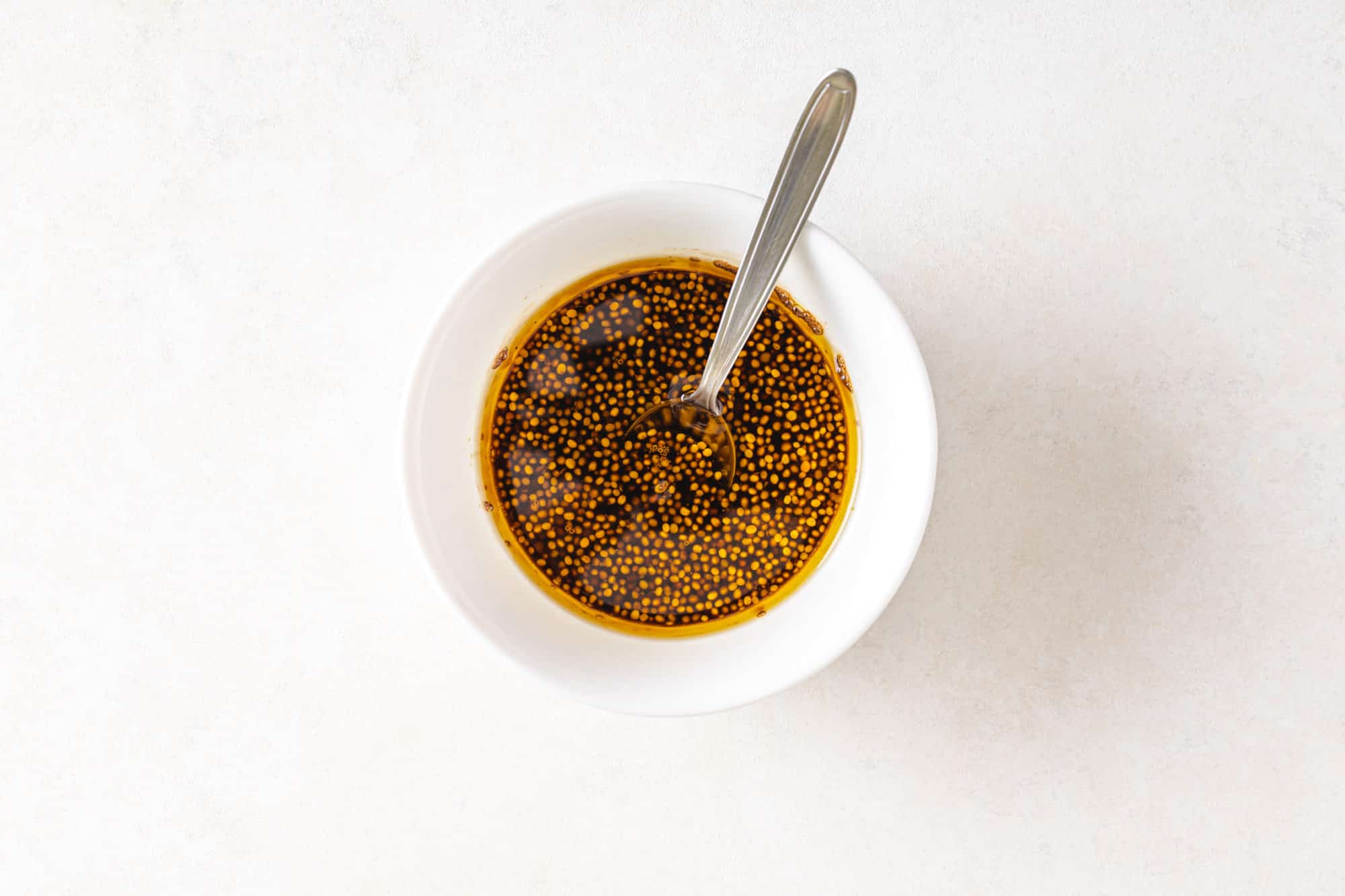 balsamic dressing in a white bowl with a spoon.