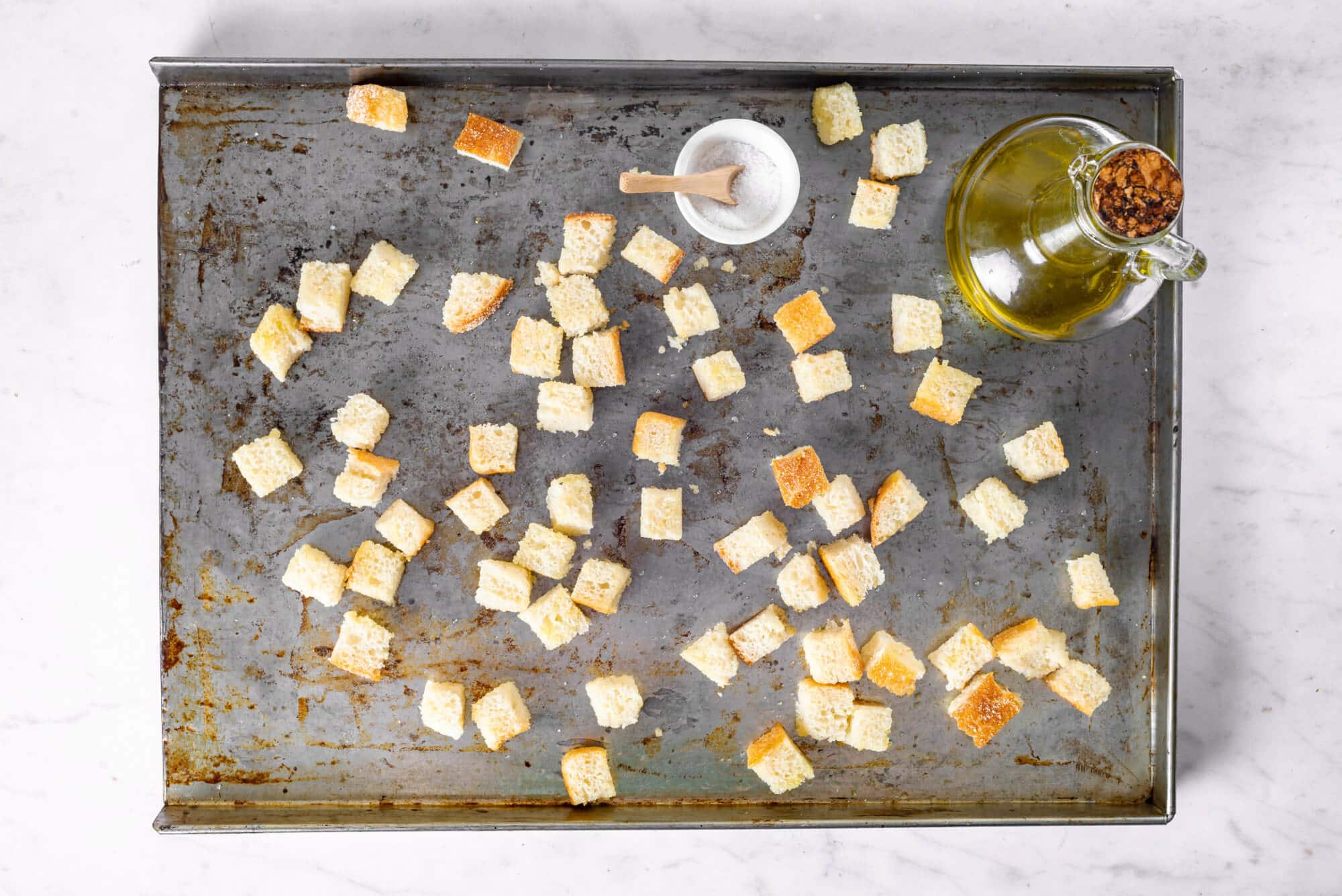 bread-pieces-on-a-baking-tray-with-a-small-bowl-of-salt-and-a-glass-dish-of-olive-oil