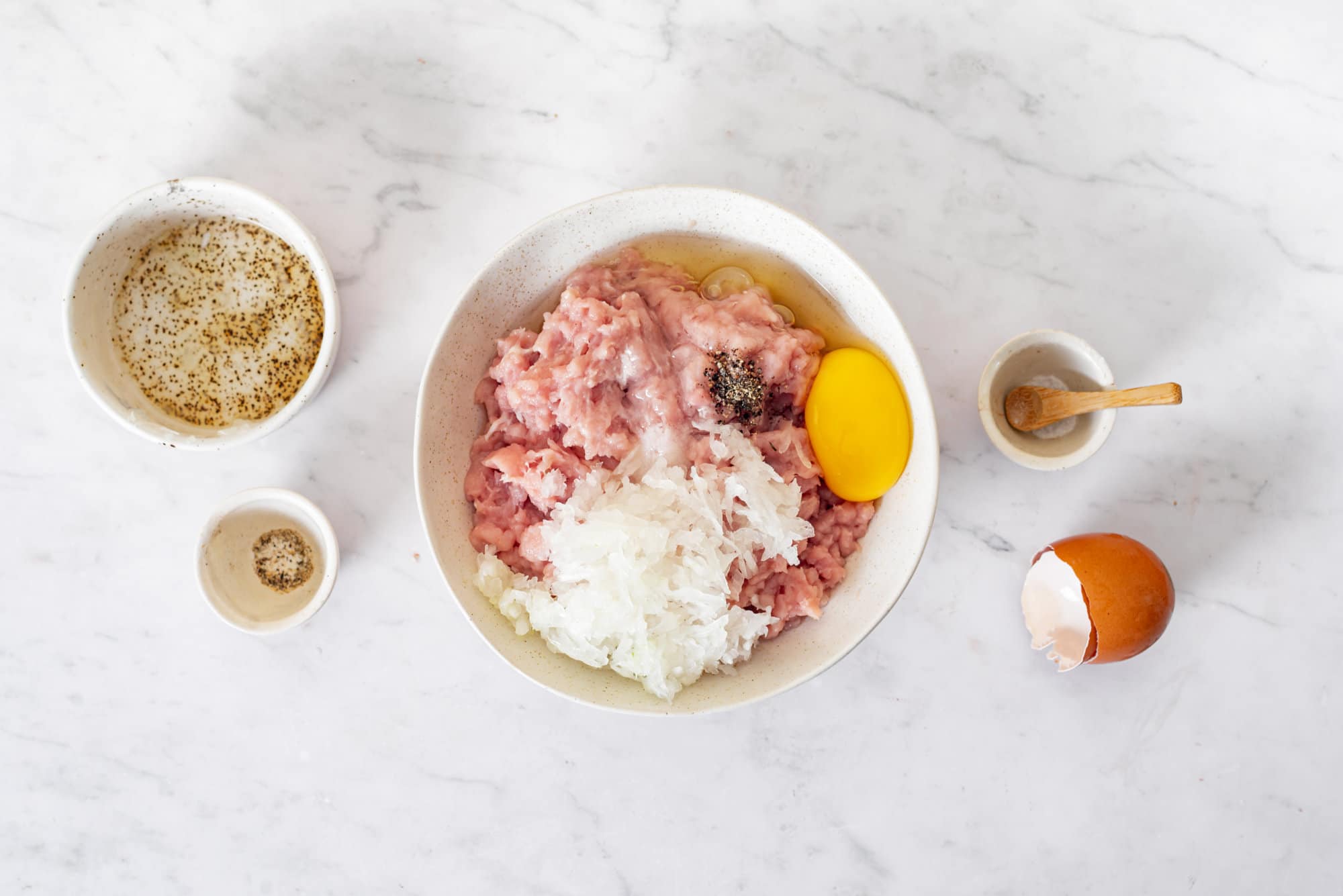 ingredients-for-meatballs-in-a-white-bowl-with-bowls-around