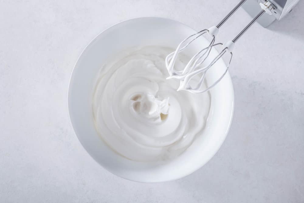 beaten-fluffy-egg-whites-in-a-white-bowl-with-hand-mixer