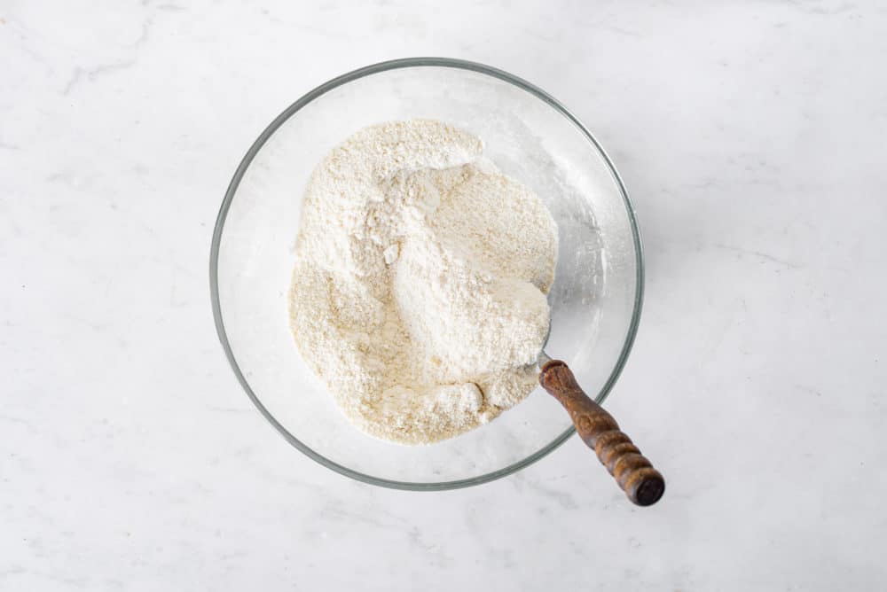 Flour in a glass bowl with a spoon.