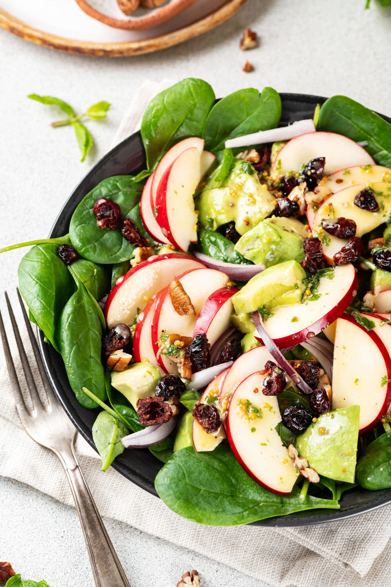 A bowl of apple, spinach, avocado salad.