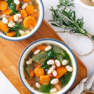 tuscan soup in white bowl on a wooden board.