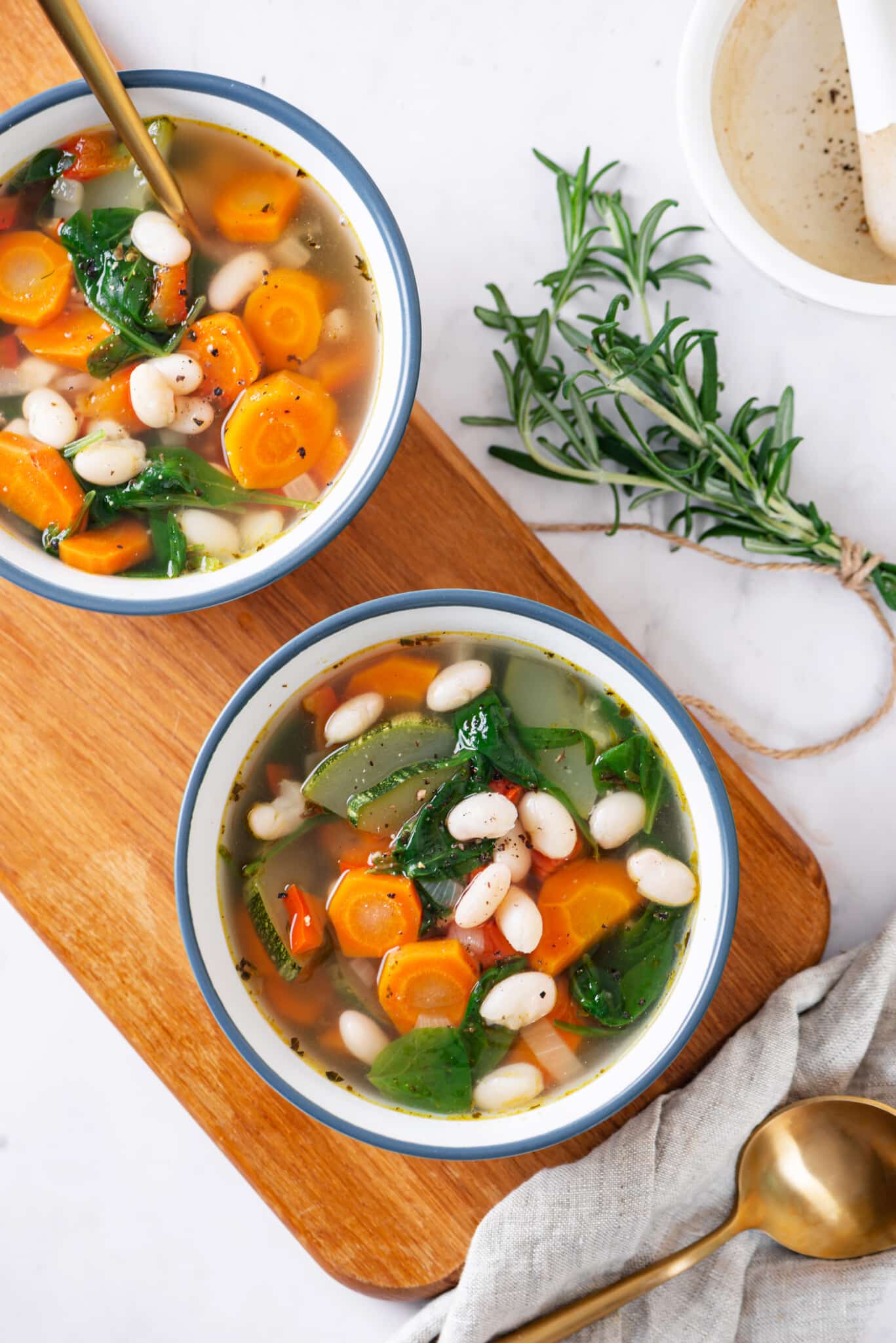 tuscan soup in white bowl on a wooden board.