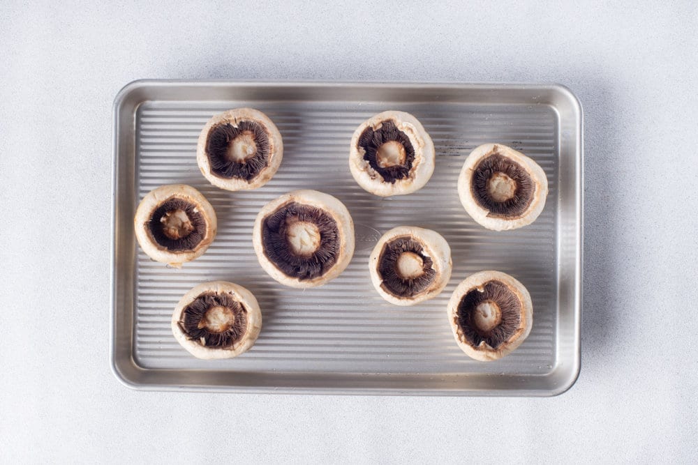 a baking tray with mushroom caps on top.