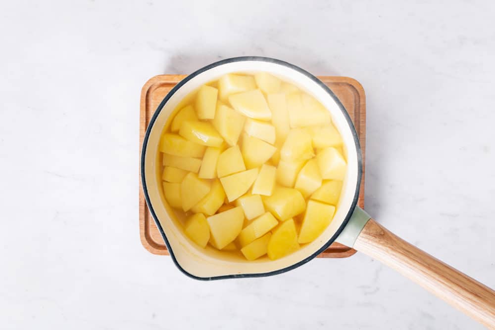 Chopped potatoes cooking in a saucepan.