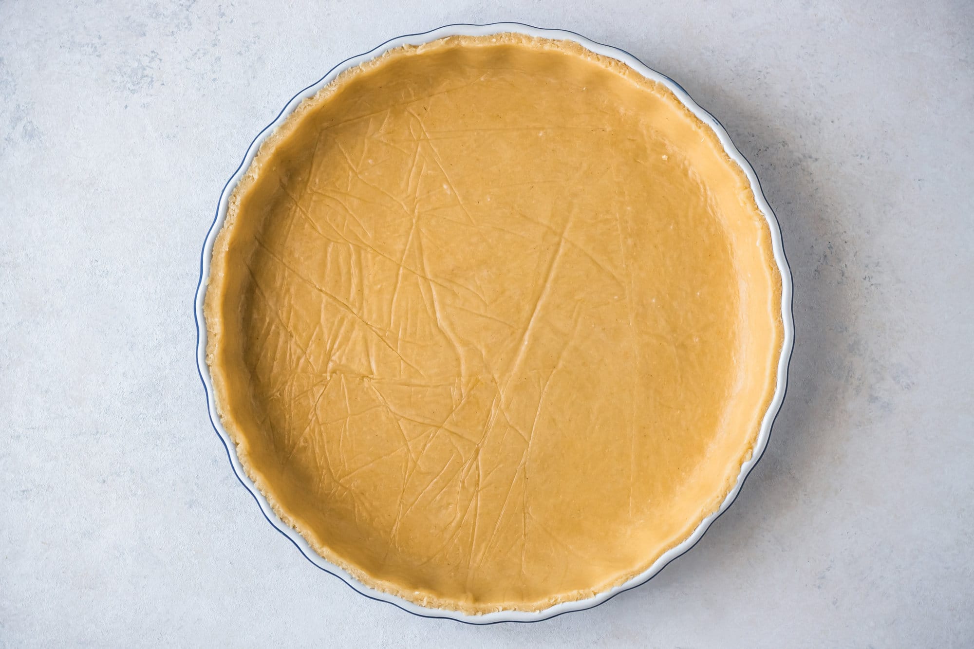 A baking tray lined with dough for apple tart. 