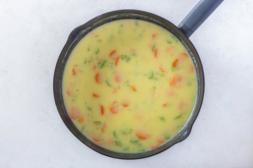 chicken pot pie filling cooking in a black skillet.