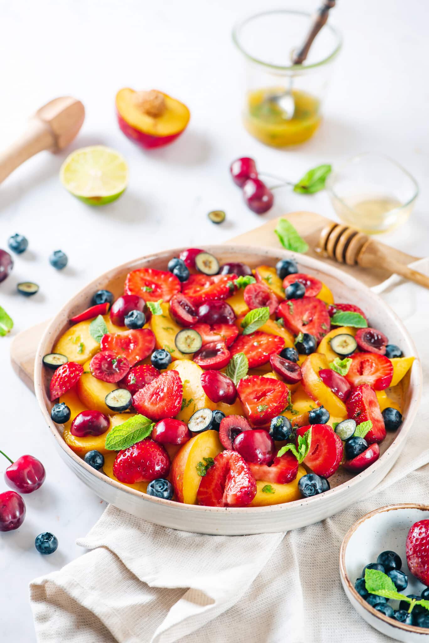 a white bowl filled with chopped summertime salad and mint leaves.