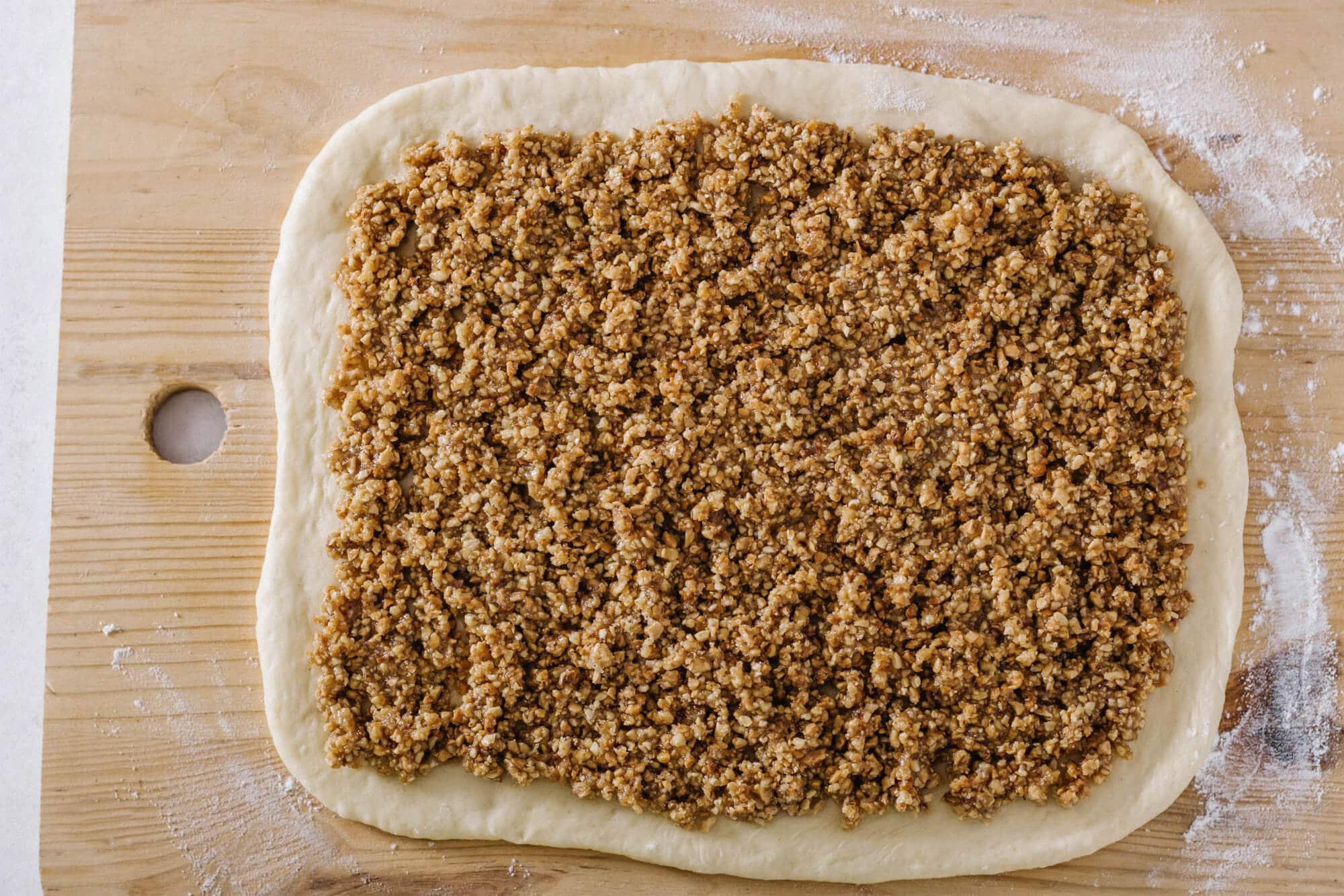 walnut-roll-dough-on-a-wooden-board-with-nut-filling-and-flour