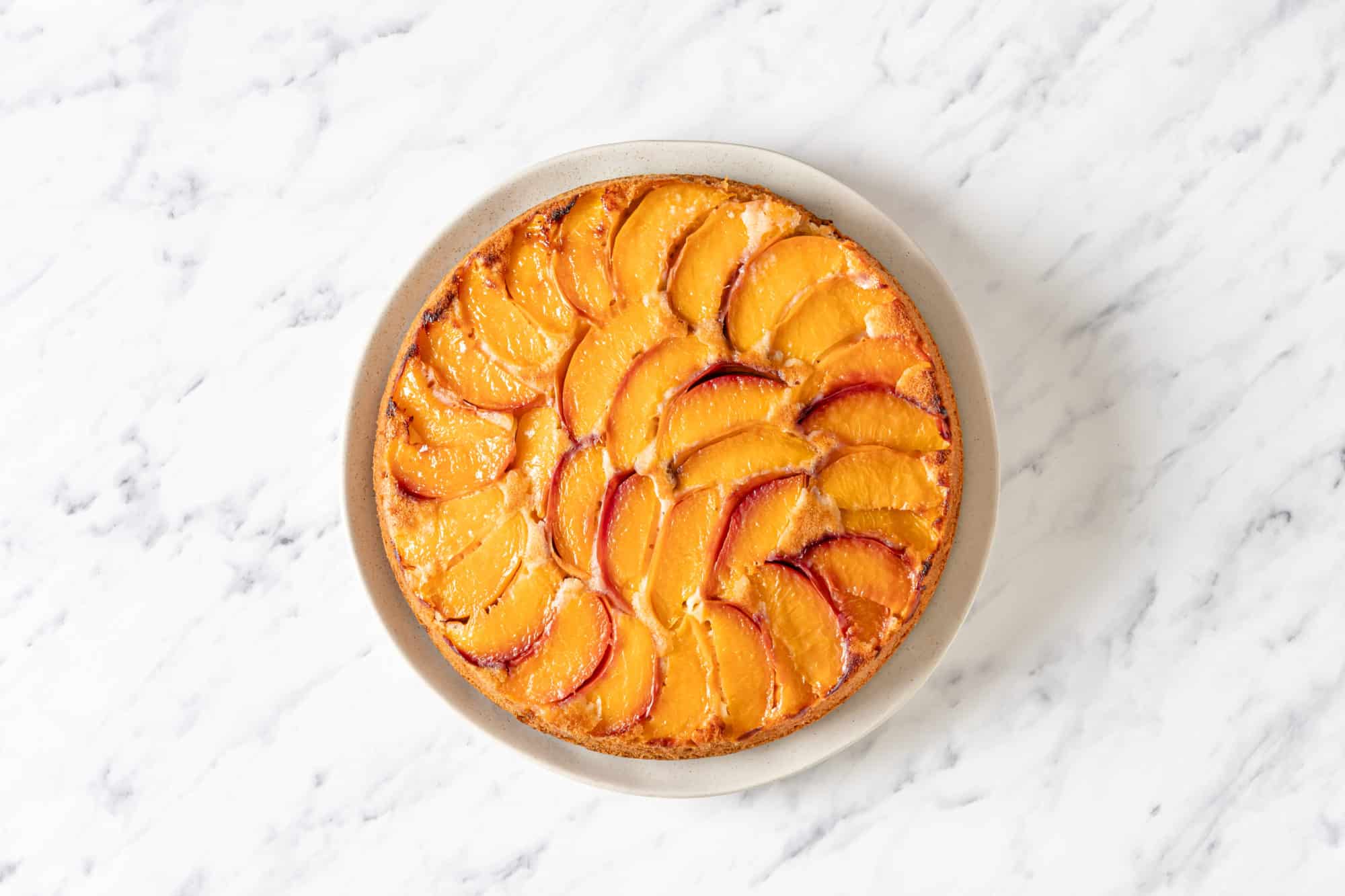 Baked upside down peach cake on a plate.