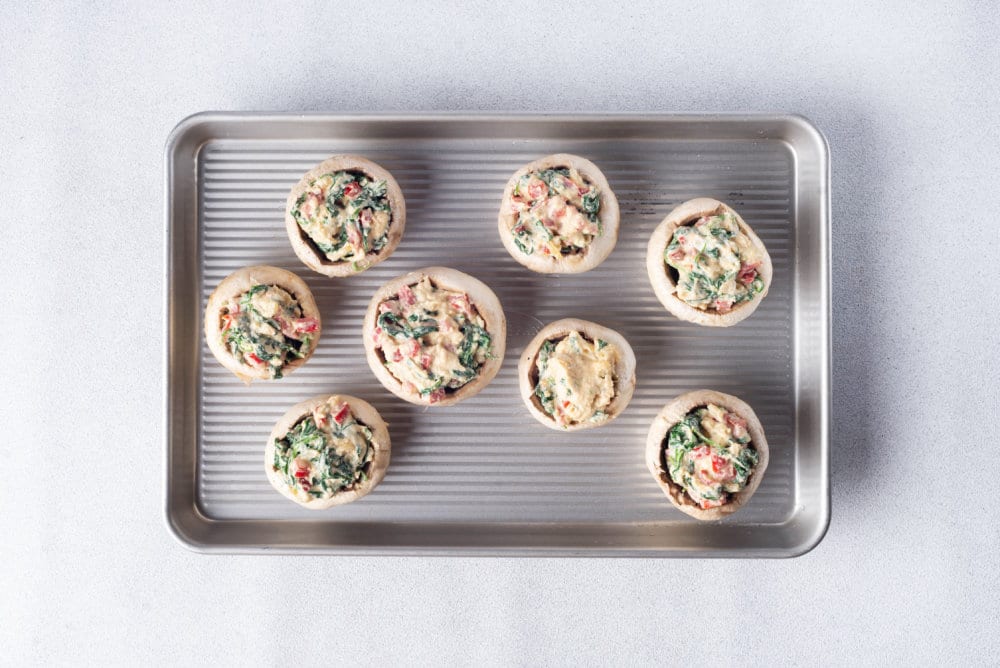 unbaked stuffed mushrooms on a baking tray.