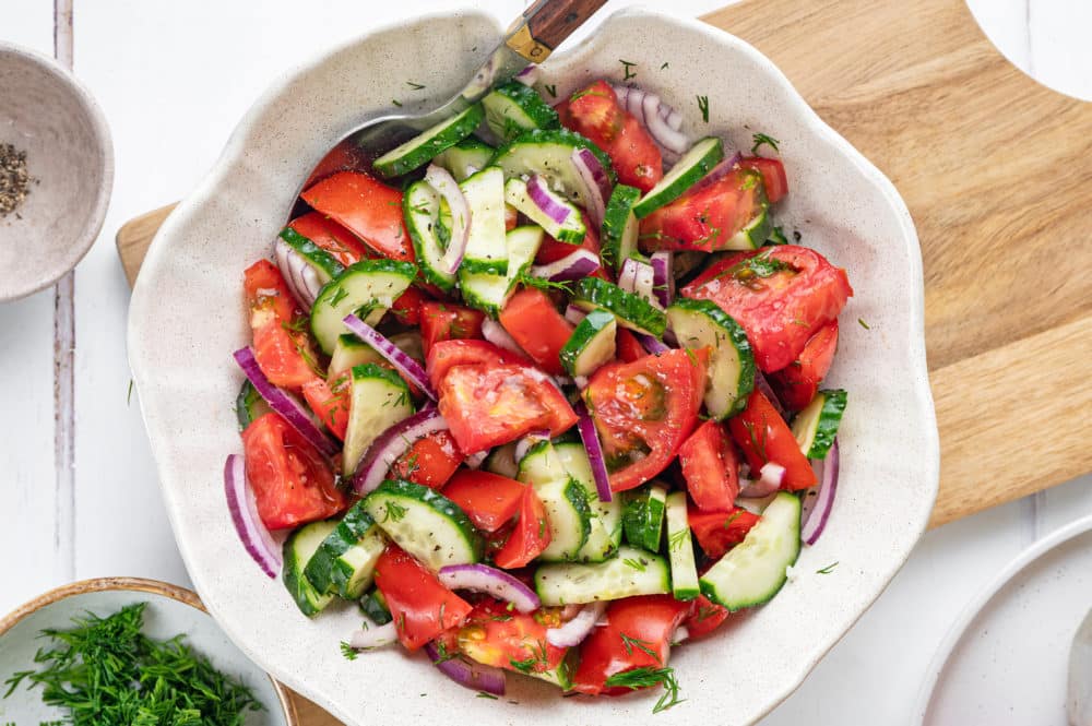 summer-salad-in-a-white-bowl-with-a-spoon-on-a-wooden-board