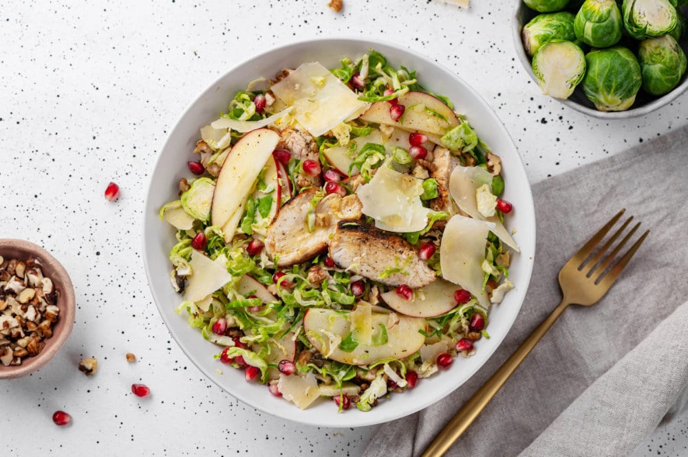 salad in a bowl with a gold fork on the side on a grey towel.