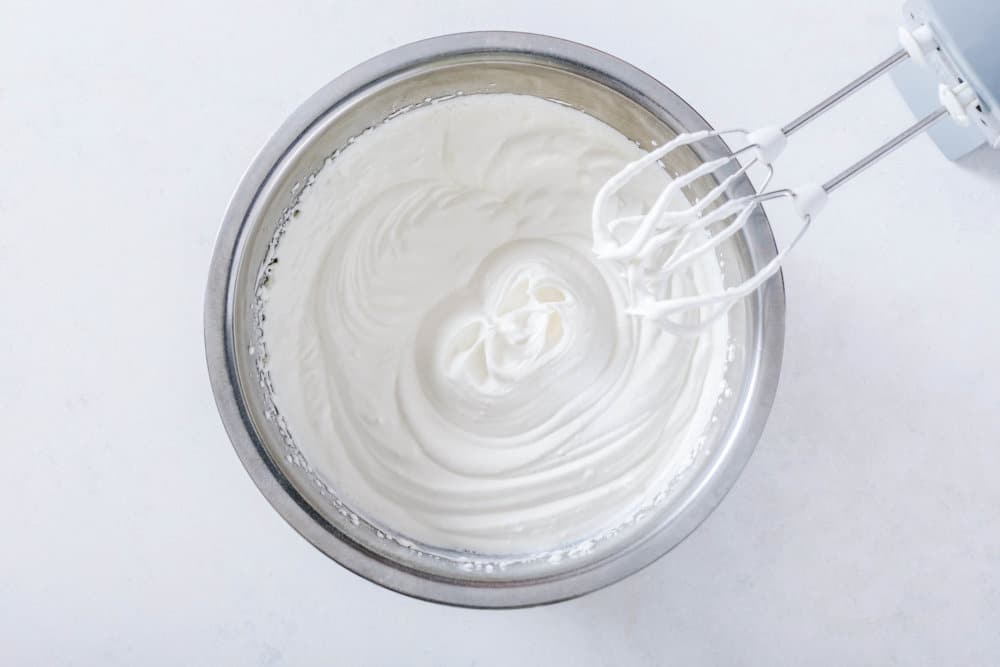 Cream with hand mixers in a silver bowl.