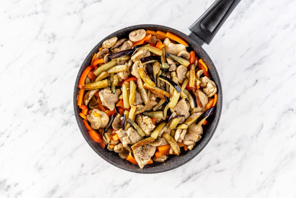 a black skillet with veggies and chicken in it.