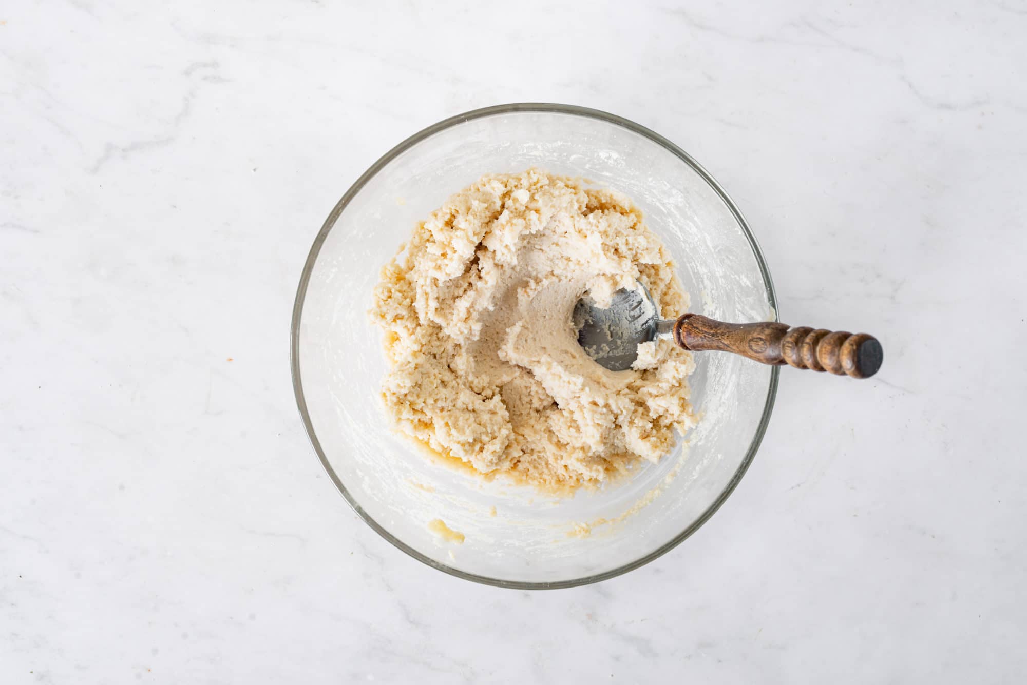 Peach cobbler dough in a glass bowl with a spoon.