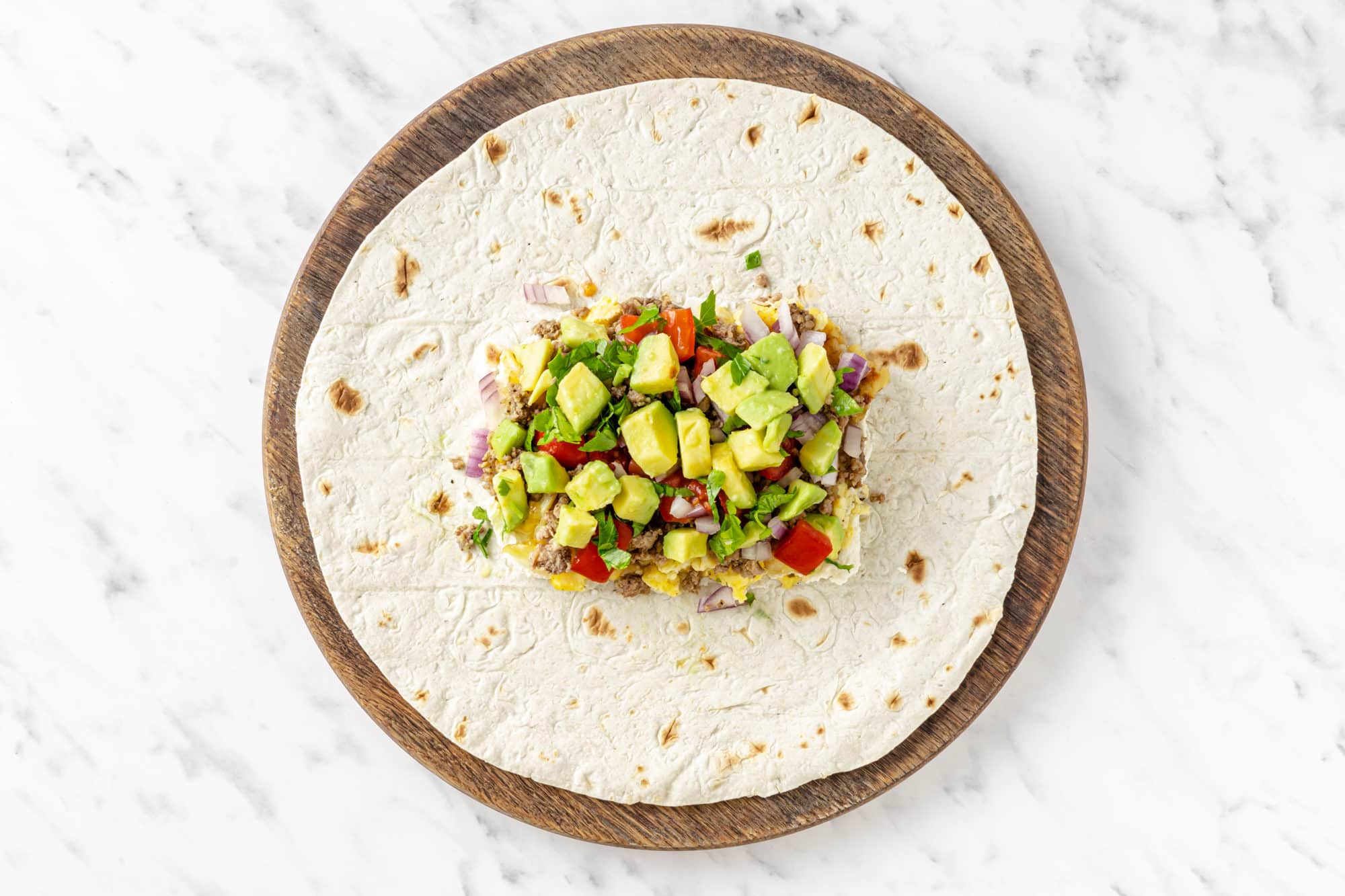 a tortilla with all of the burrito toppings in the center.