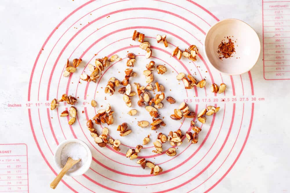 chopped nuts on a mat with spices in a bowl with salt in a small bowl.