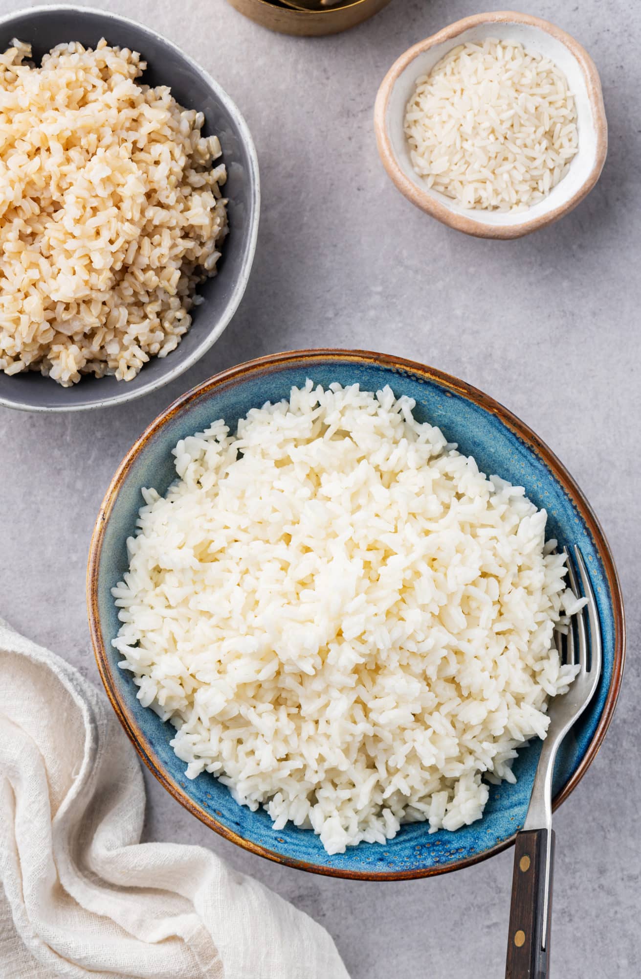 White rice in a blue bowl with a fork on the side.