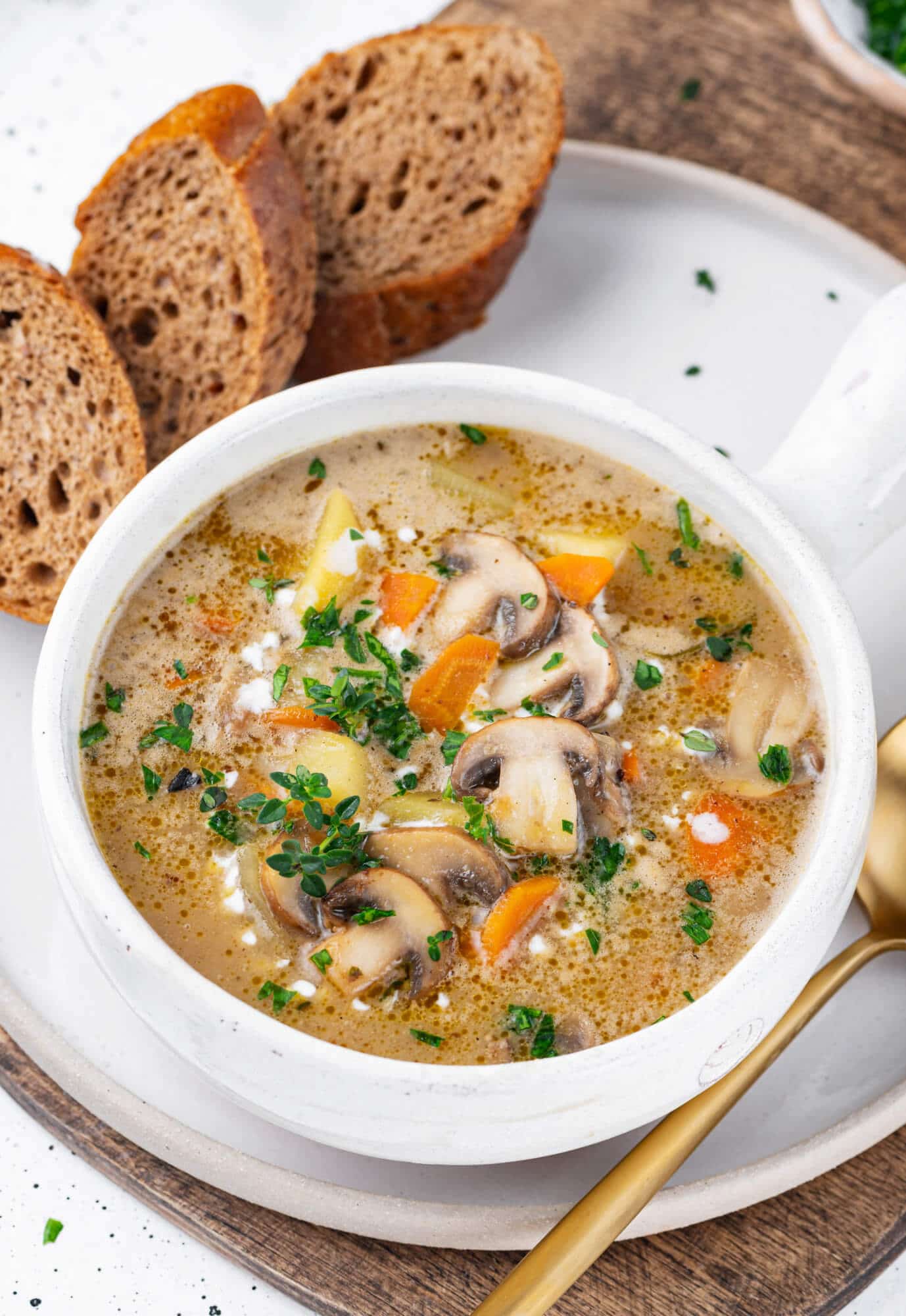 Mushroom soup in a white bowl with a gold spoon on the side.