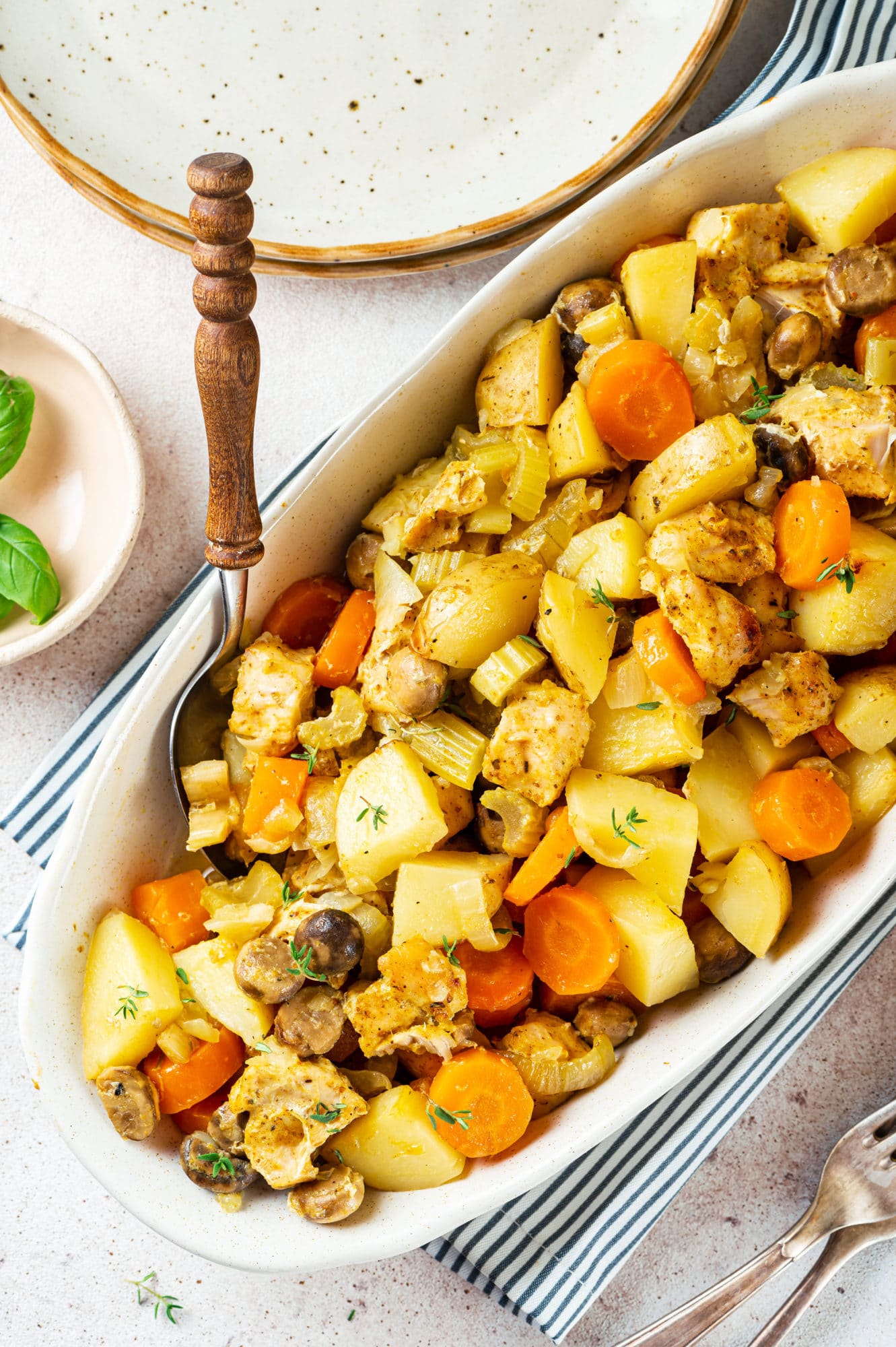 roasted chicken and veggies in a white bowl with a serving spoon.